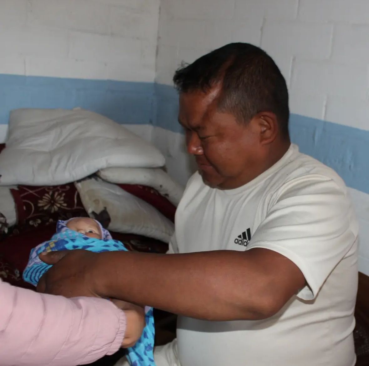A father practising newborn care during a community session